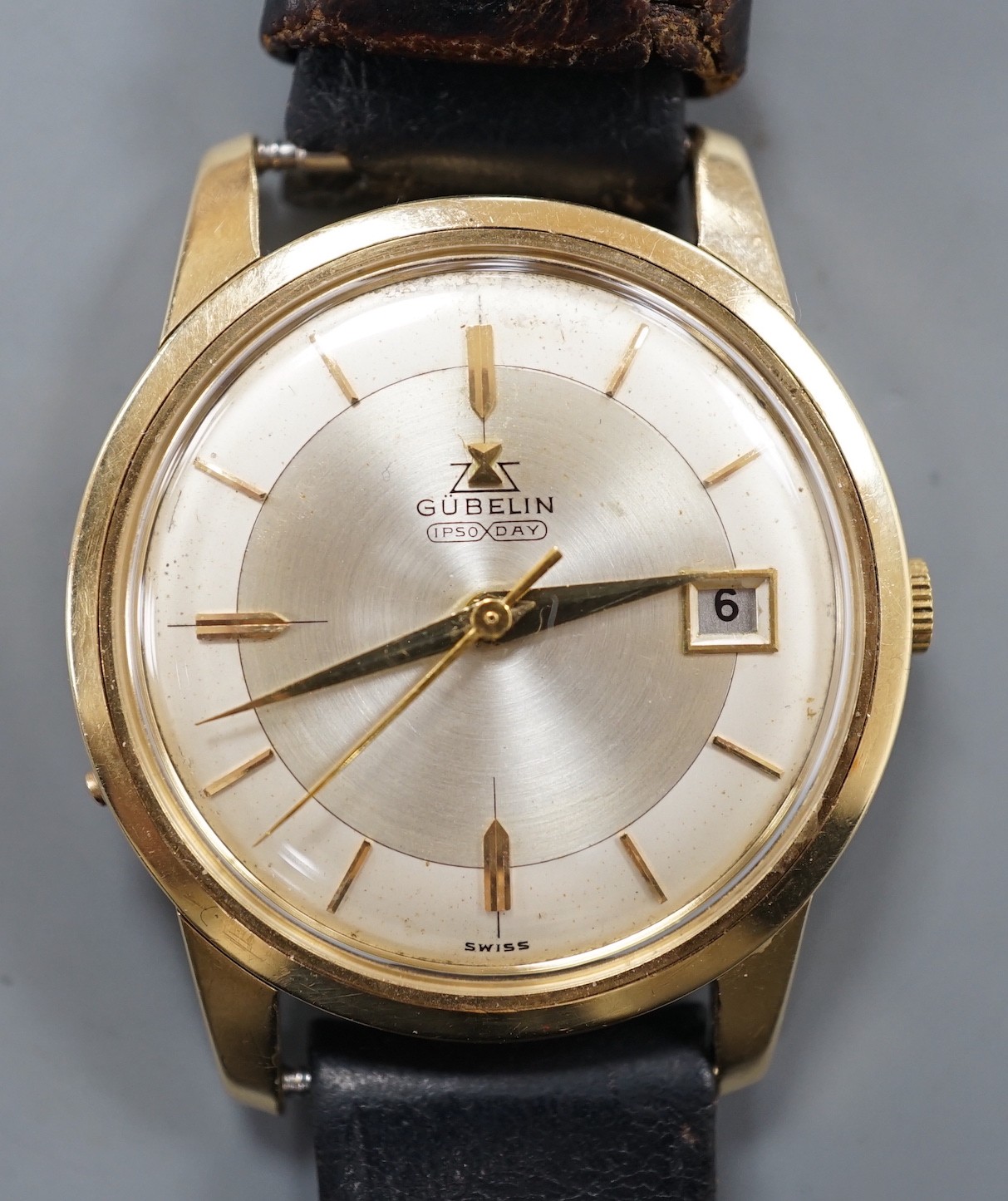 A gentleman's 14ct gold Gubelin Ipso Day automatic wrist watch, with baton numerals and date aperture, on associated leather strap, the case back with engraved initials, case diameter 35mm